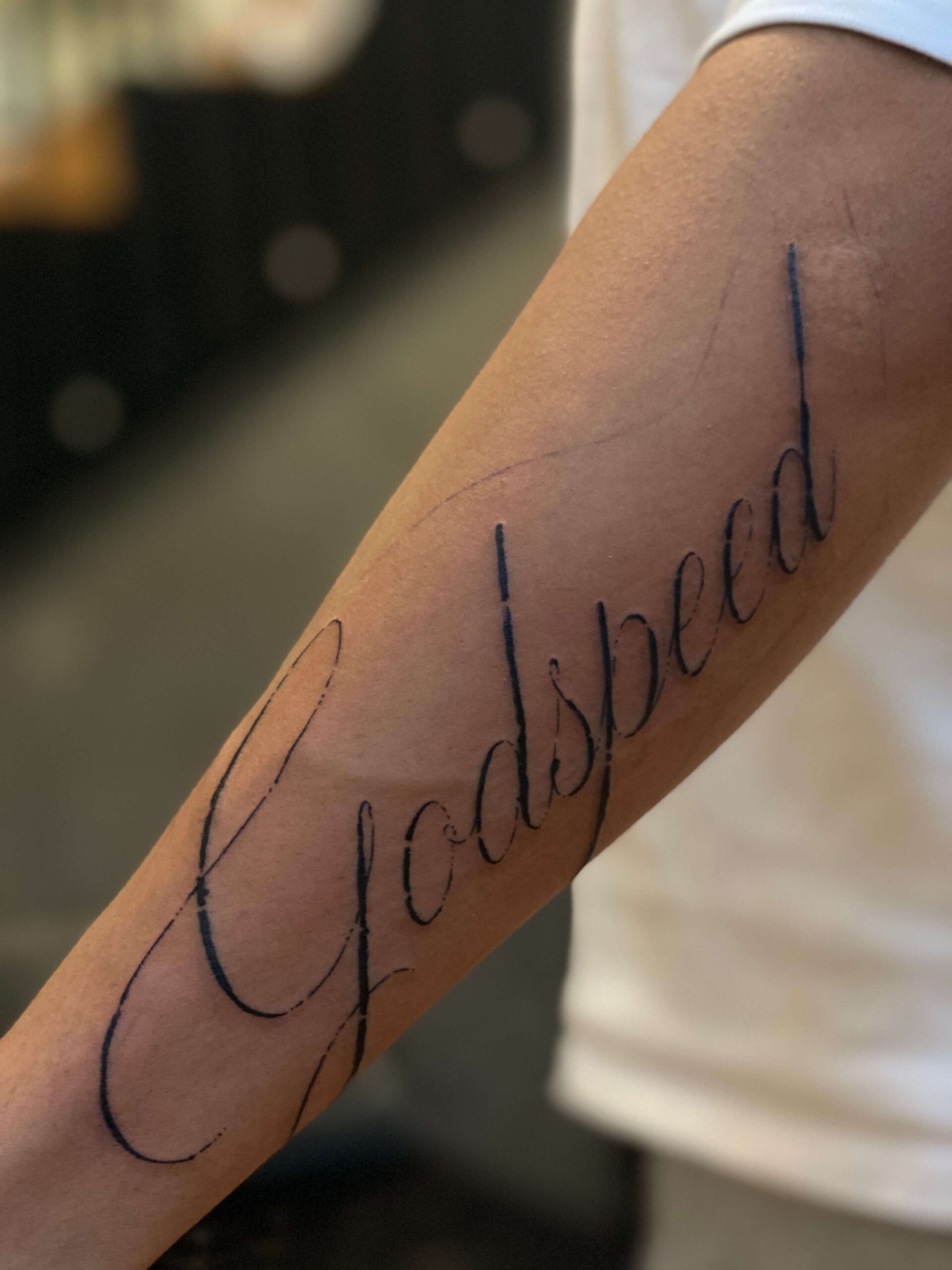 Skrift tatovering med ordet Godspeed på underarm – Timeless Studio Roskilde