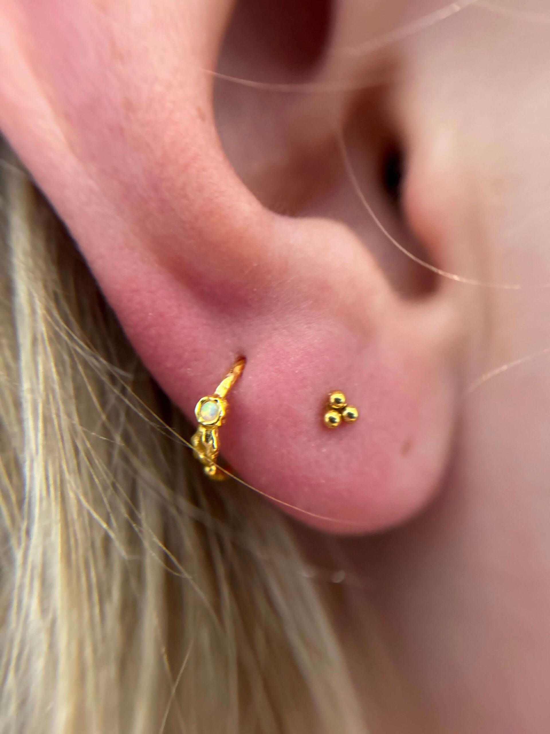Styling af øre med flere ørepiercinger og forgyldte smykker – Timeless Studio Roskilde